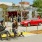 a couple of people sit on a bench in front of a red car