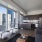 Spacious and well lit living room with wood flooring, large windows and open access to the kitchen